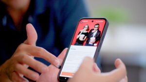 Hands holding a smartphone with the screen displaying a property and resident app.
